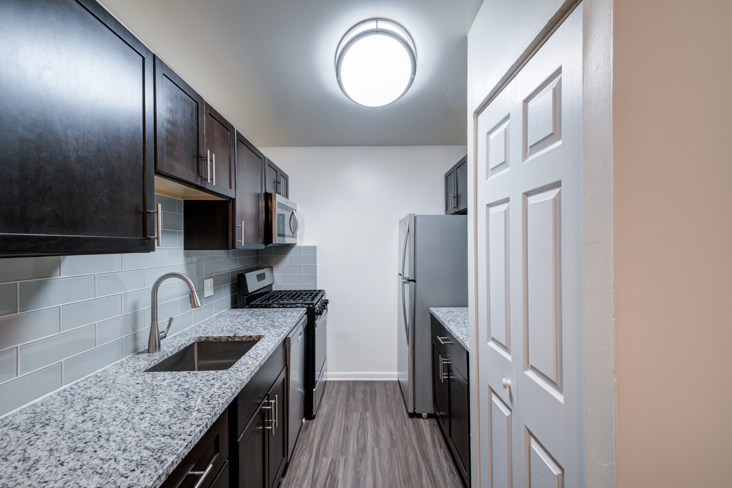 A kitchen with black cabinets and a granite countertop.
