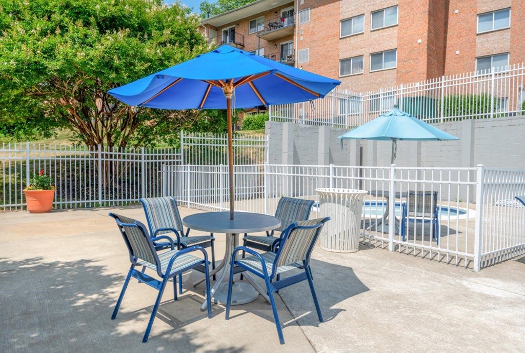 a patio with a table and chairs with umbrellas
