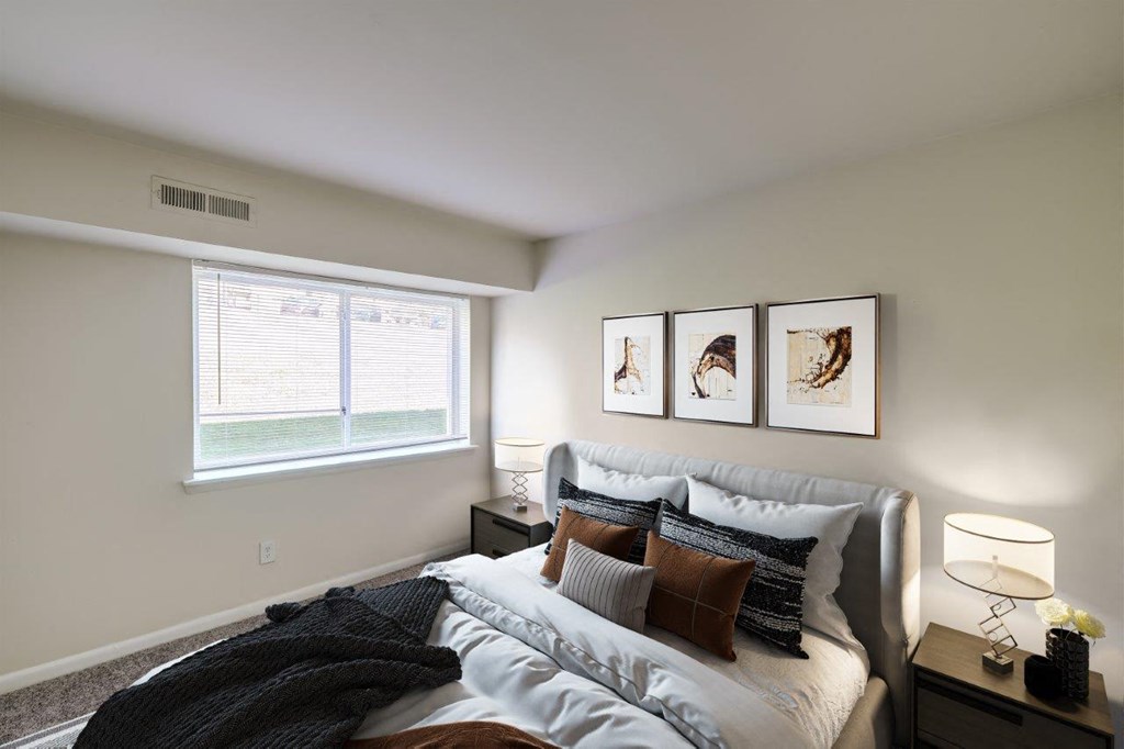 A bedroom with a bed, nightstand, and pictures on the wall.