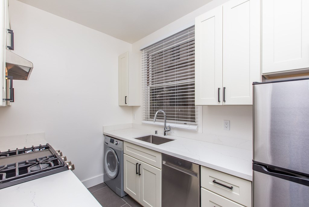a kitchen with white cabinets and stainless steel appliances and a sink