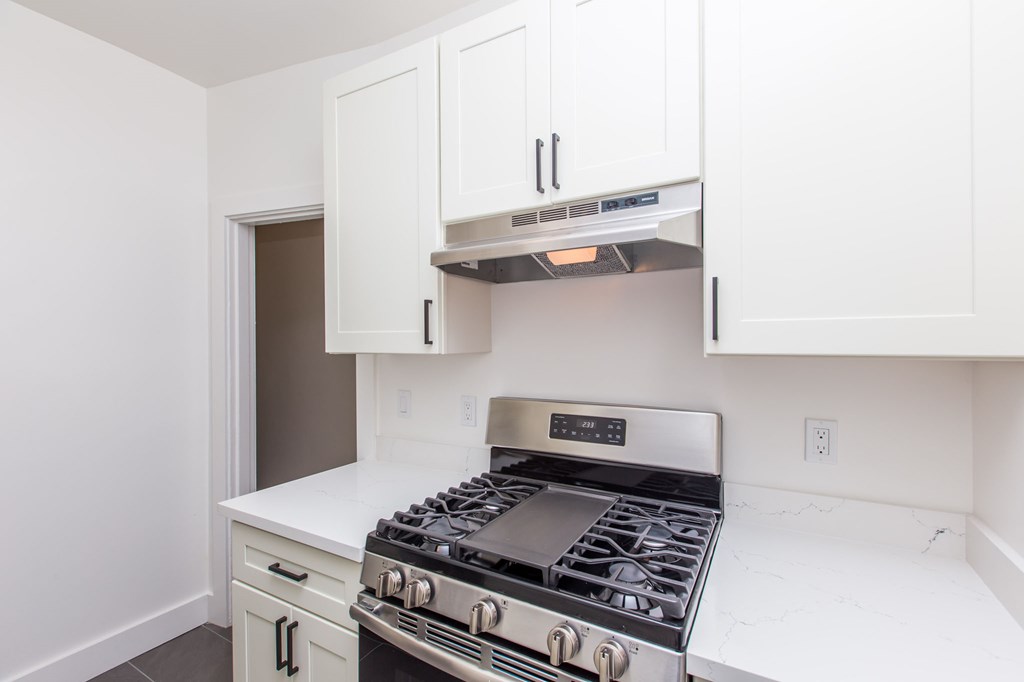 a kitchen with white cabinets and a stove and microwave