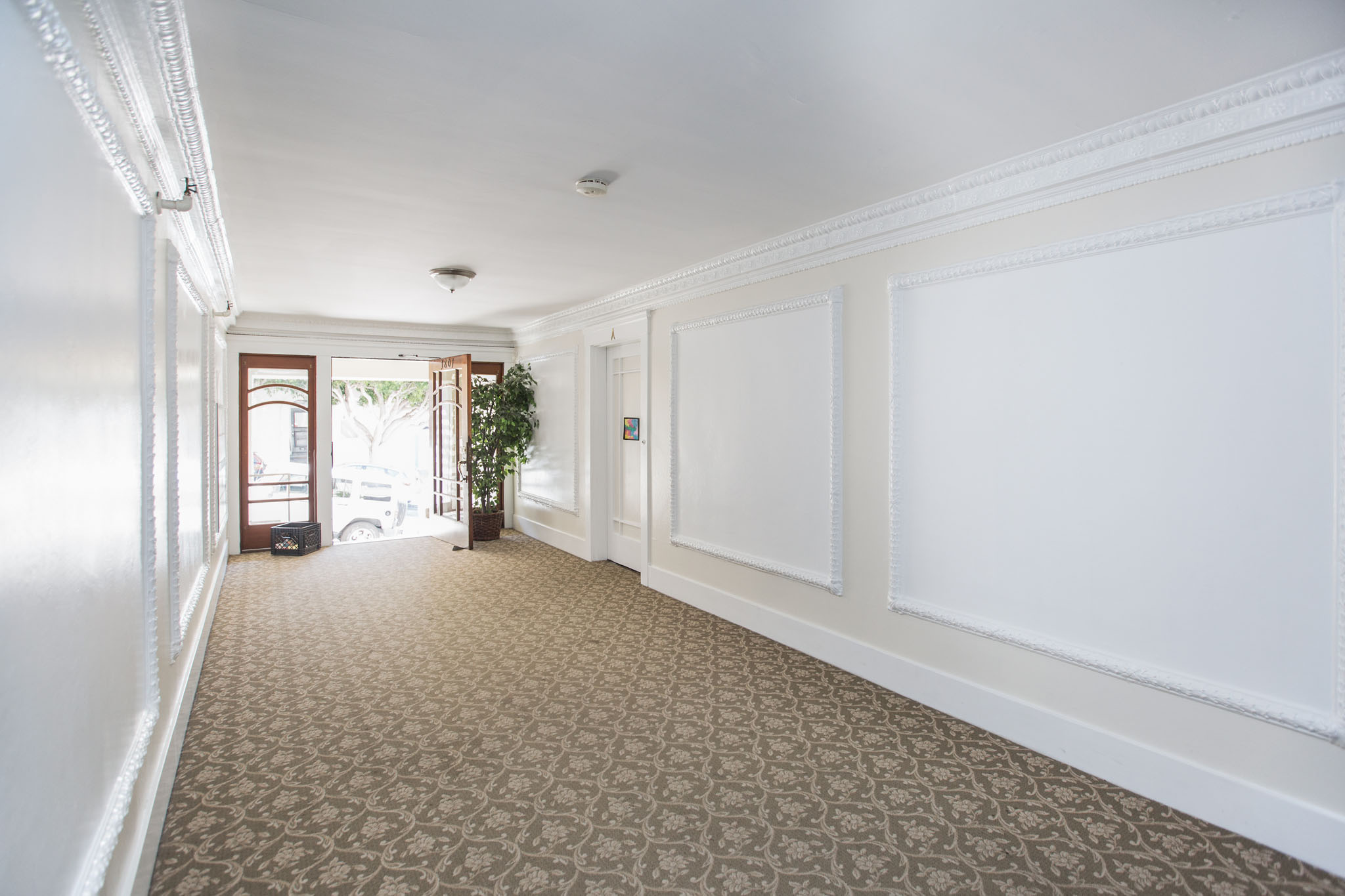 A long hallway with a carpeted floor and white walls.