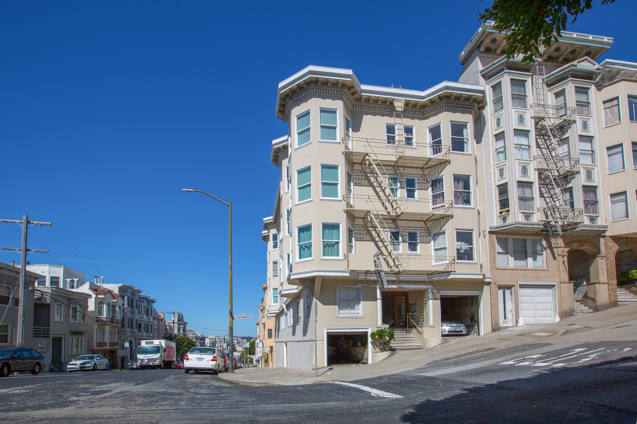 A street view of a residential area with apartment buildings and parked cars.
