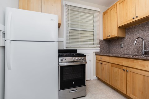 A white refrigerator stands next to a stove in a kitchen.