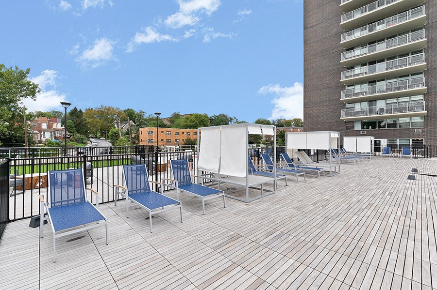 a large deck with blue lounge chairs on top of a building