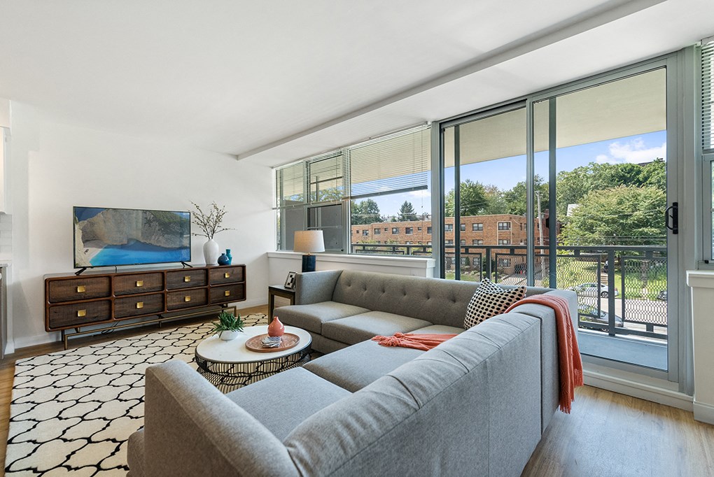 Large, grey couch in front of sliding glass doors leading out to spacious private balcony