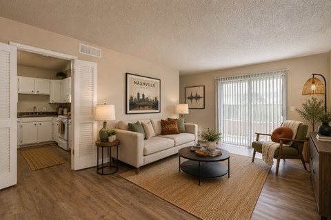 A living room with a white couch, a coffee table, and a painting of Nashville on the wall.