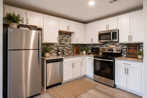 A kitchen with a stainless steel refrigerator and white cabinets.