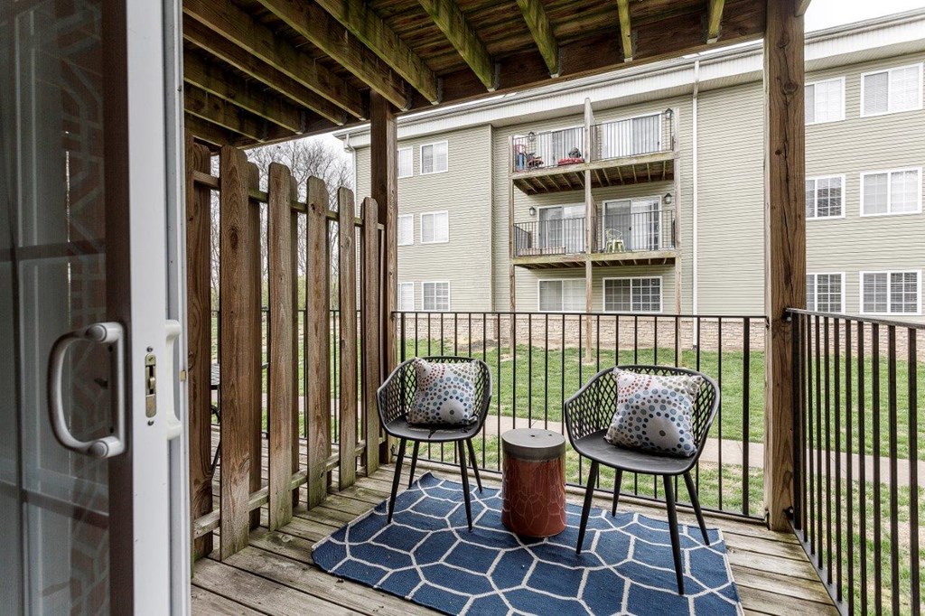 a patio with two chairs and a table on a wooden deck