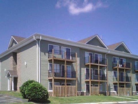 a green apartment building with balconies and a blue sky