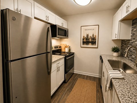 A kitchen with a fridge, microwave, and a picture of a city skyline.