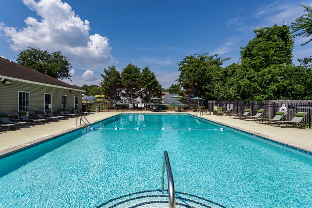 a swimming pool with chairs and a building in the background