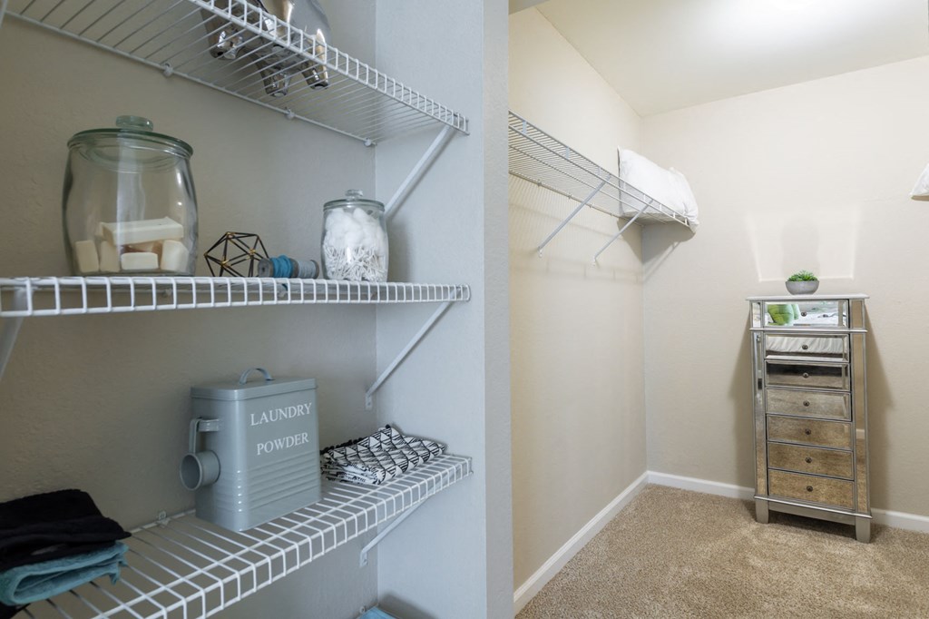 a closet with shelves and a dresser in a home with a laundry room