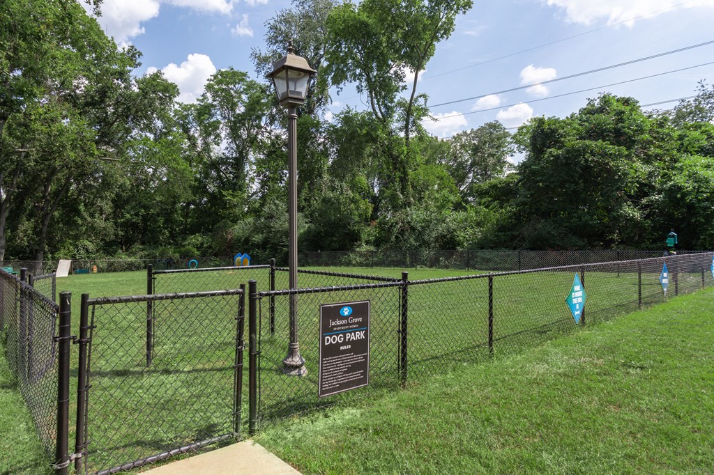 a fenced in dog park with a sign on a fence