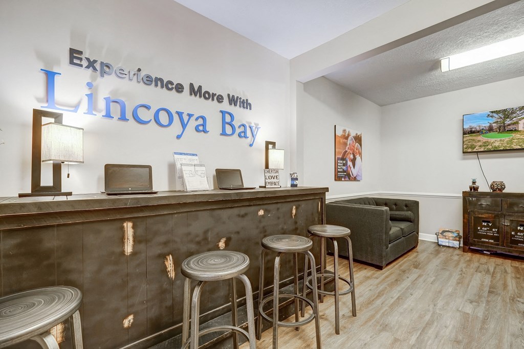 a lobby with a bar with four stools and a couch
