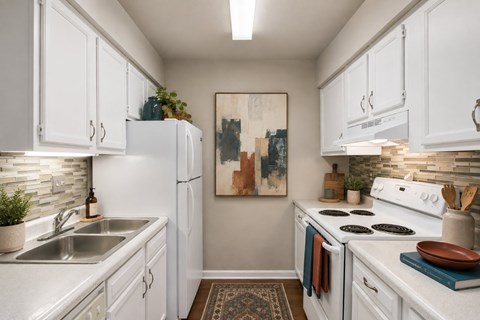 A kitchen with white cabinets and a white stove top oven.