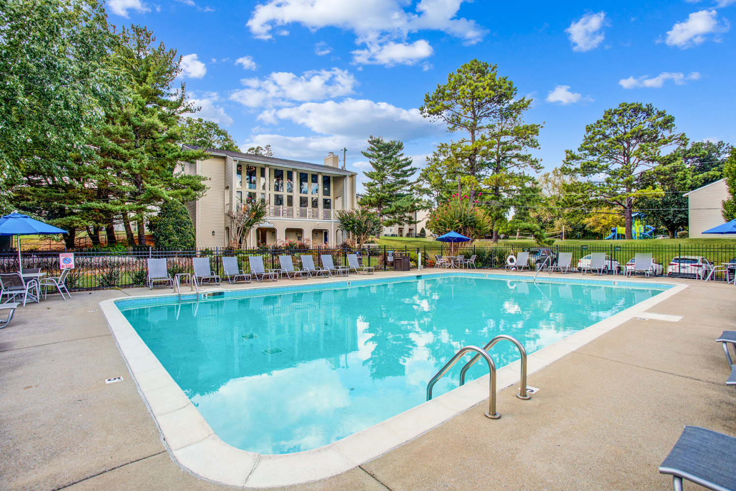 a swimming pool with chairs and a building in the background