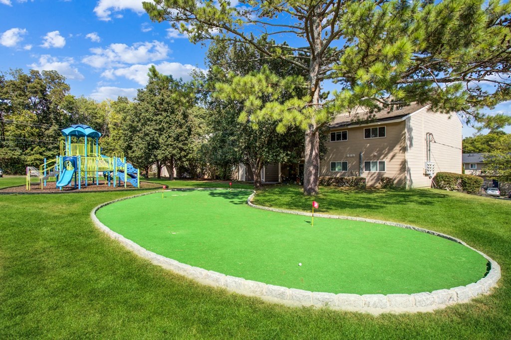 a backyard putting green with a playground and a house