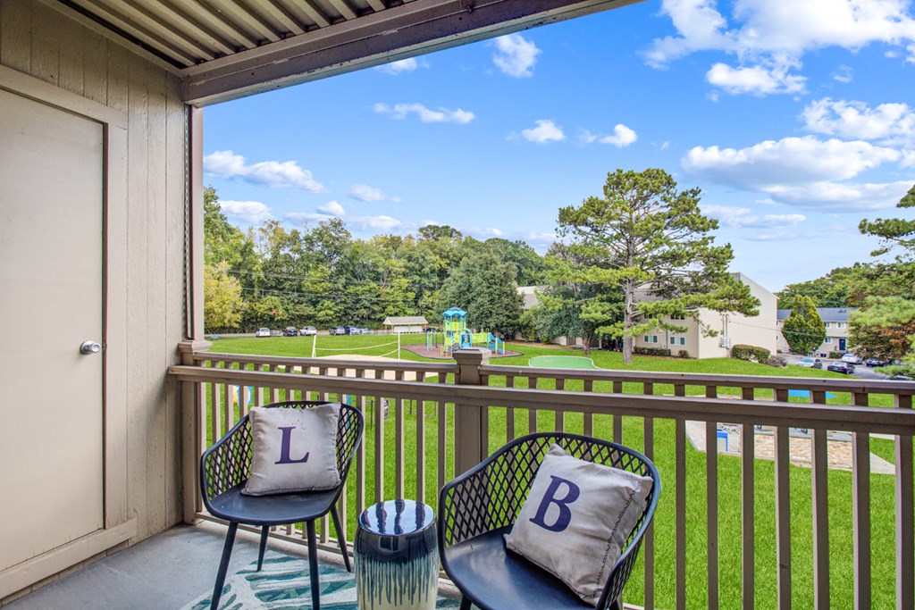 a balcony with two chairs and a view of a park