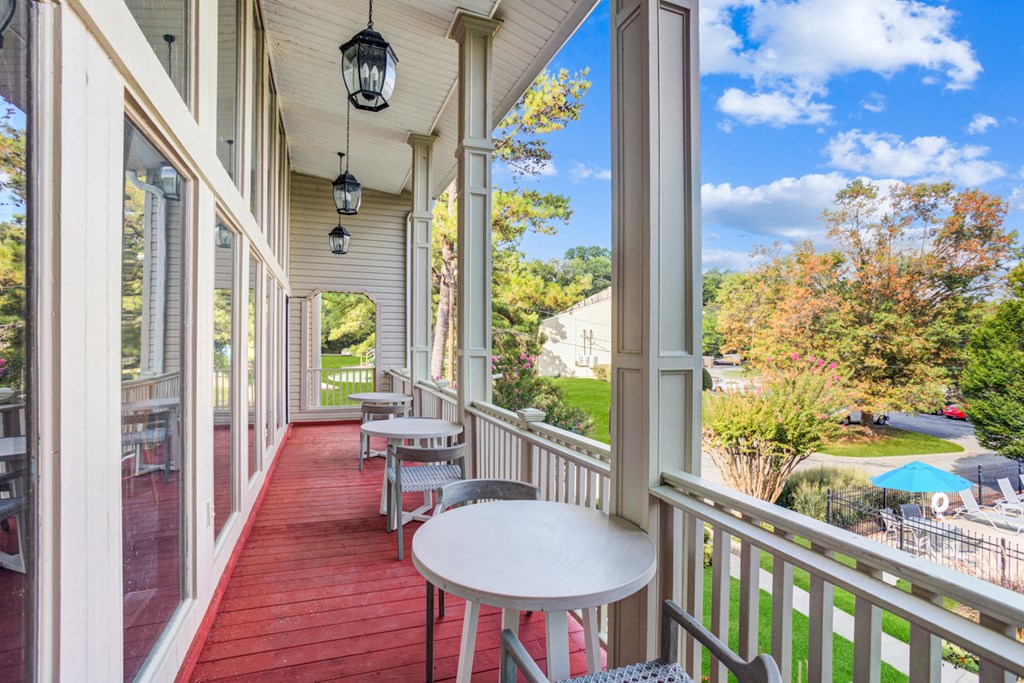 a covered porch with tables and chairs and large windows