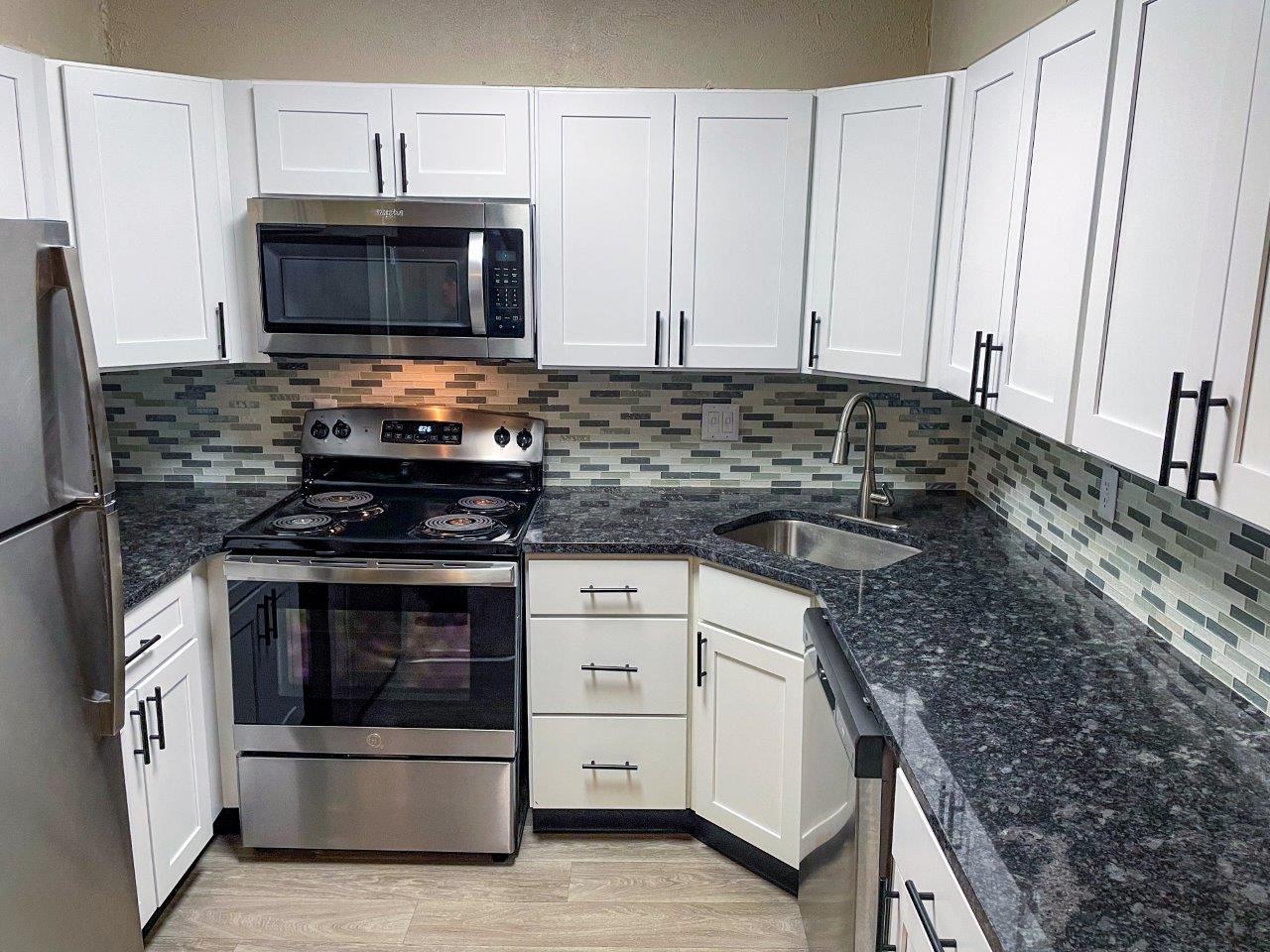 A kitchen with white cabinets and a black stove top.