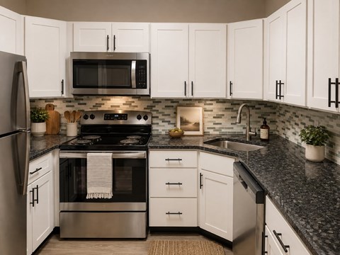 A modern kitchen with white cabinets and a black countertop.