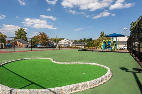 a playground with green grass and a heart shaped patch of turf