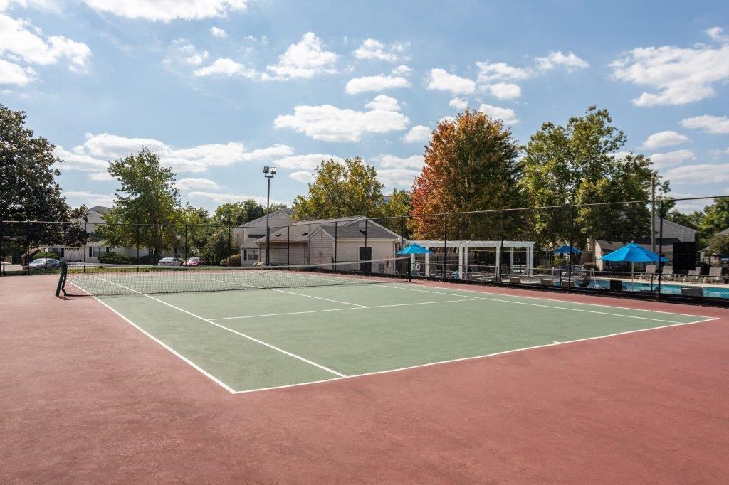 a tennis court with trees and a building in the background
