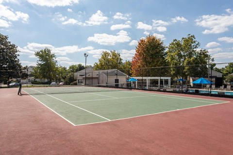 a tennis court with trees and a building in the background