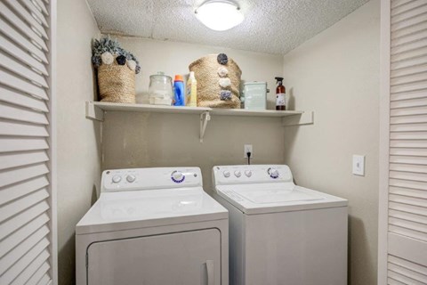 a white washer and dryer in a laundry room with a shelf above them