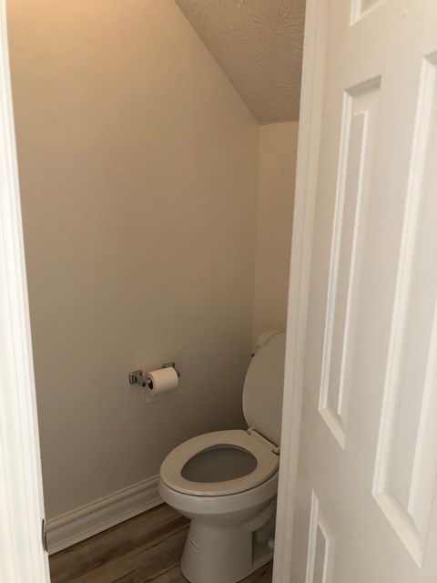 A white toilet in a small bathroom with a white door.