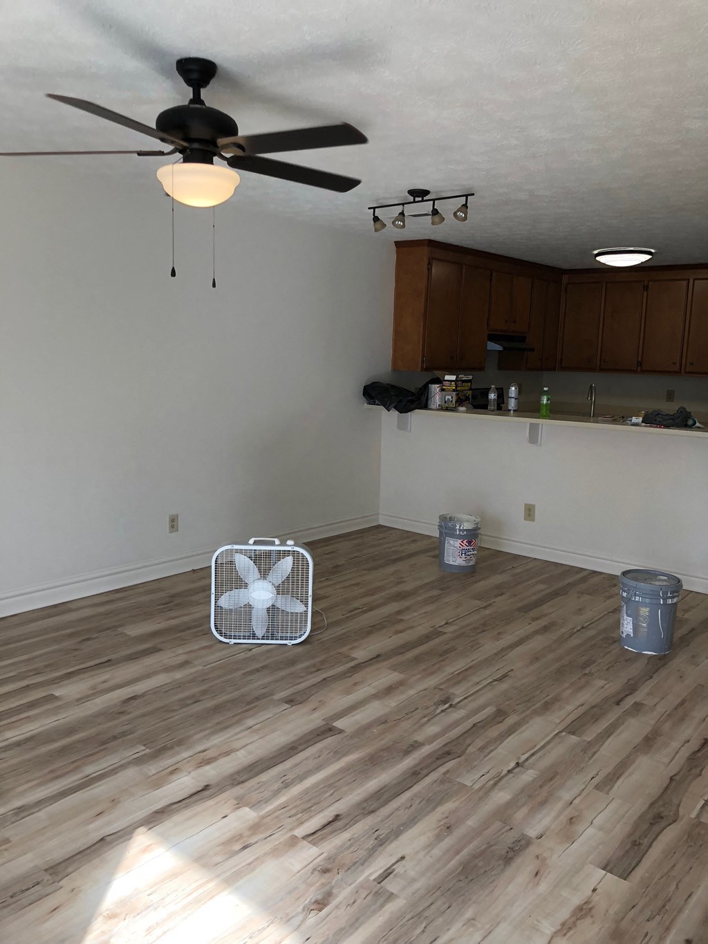 an empty living room with wood floors and a ceiling fan