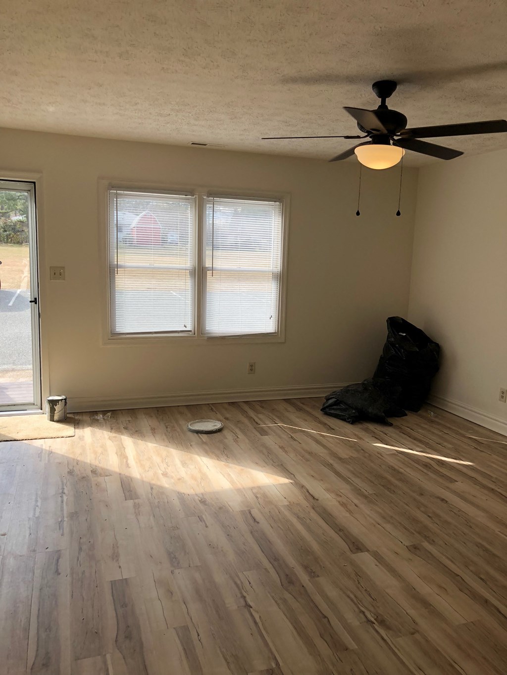 an empty living room with wood floors and a ceiling fan