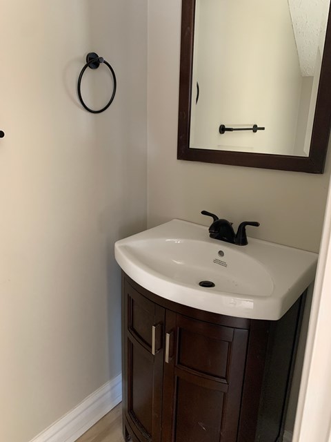 A bathroom sink with a brown cabinet and a mirror above it.