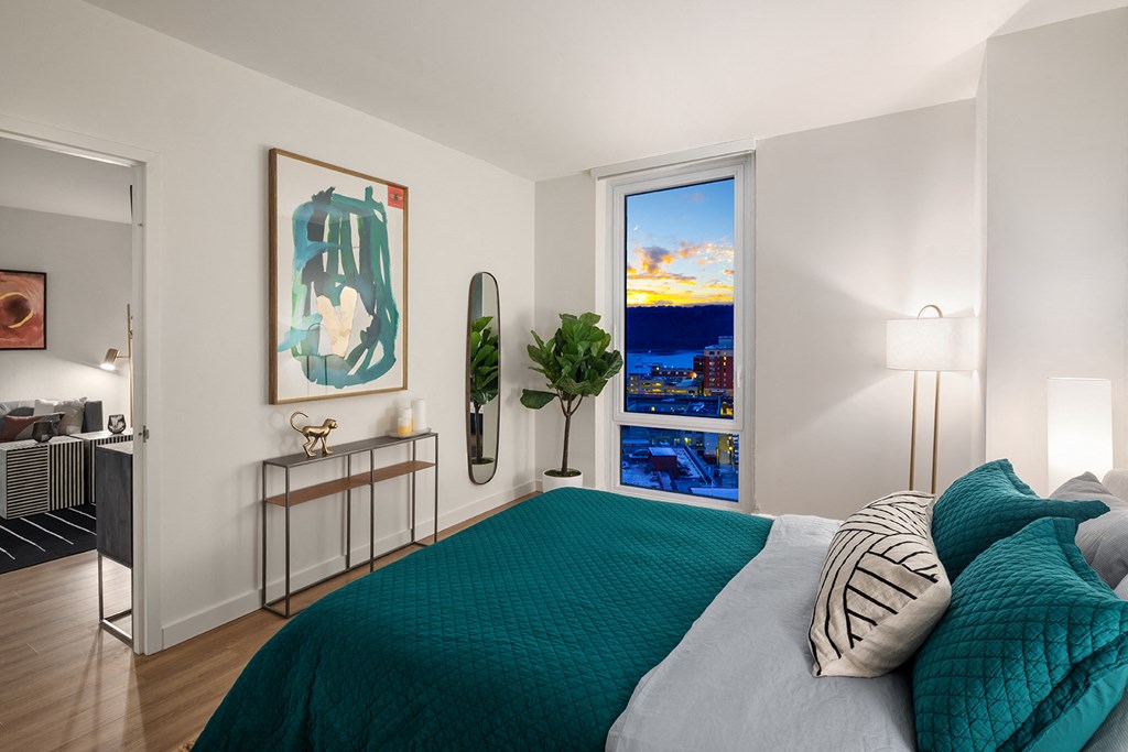 a bedroom with a bed and a window with a view of the city