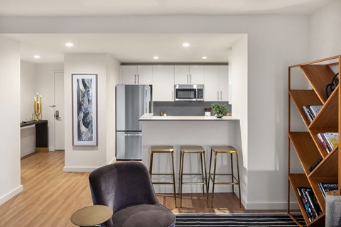 a living area with a kitchen and a bar with three stools