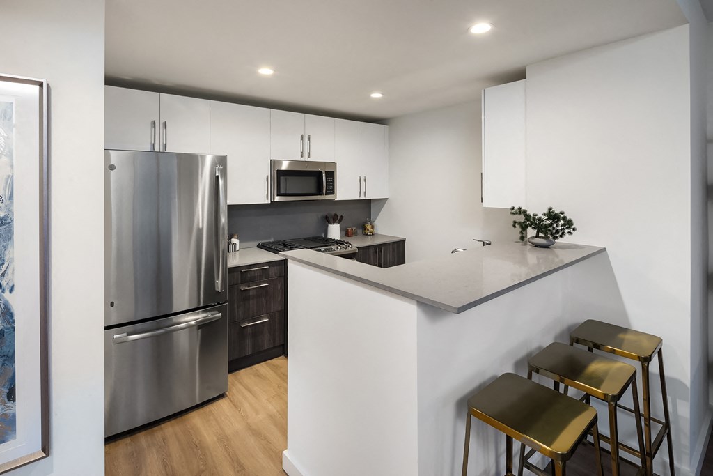 a kitchen with stainless steel appliances and a counter with three stools