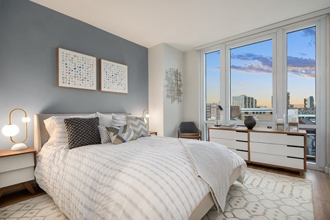 a bedroom with a large bed and a view of the city