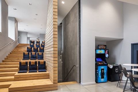 a lobby with stairs and chairs and a video game and a vending machine