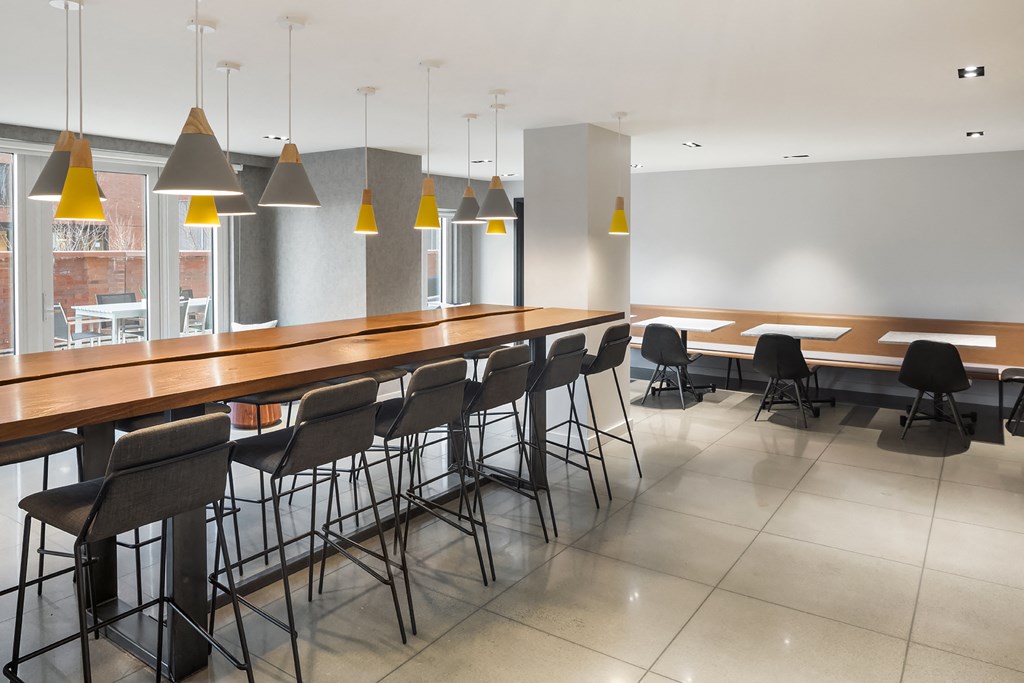 a communal area with tables and chairs and a bar with chairs