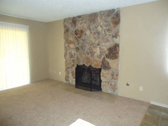 A stone fireplace in a room with a carpeted floor.
