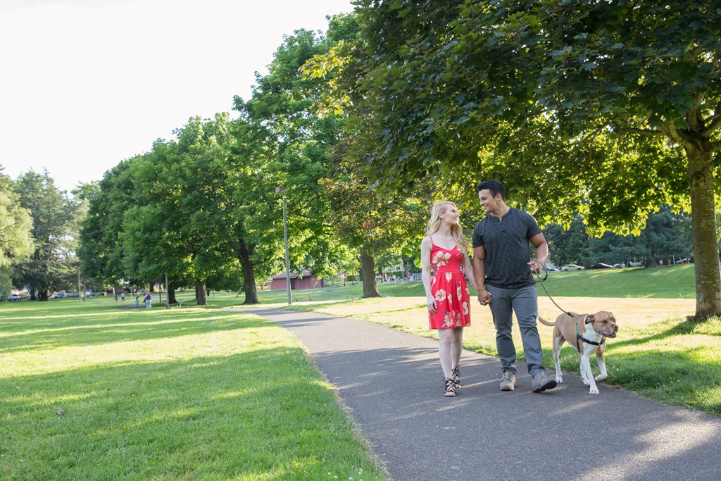 a man and woman walking their dog in a park