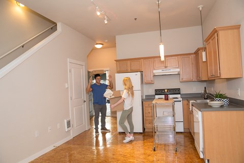 a man and a woman standing in a kitchen holding a box