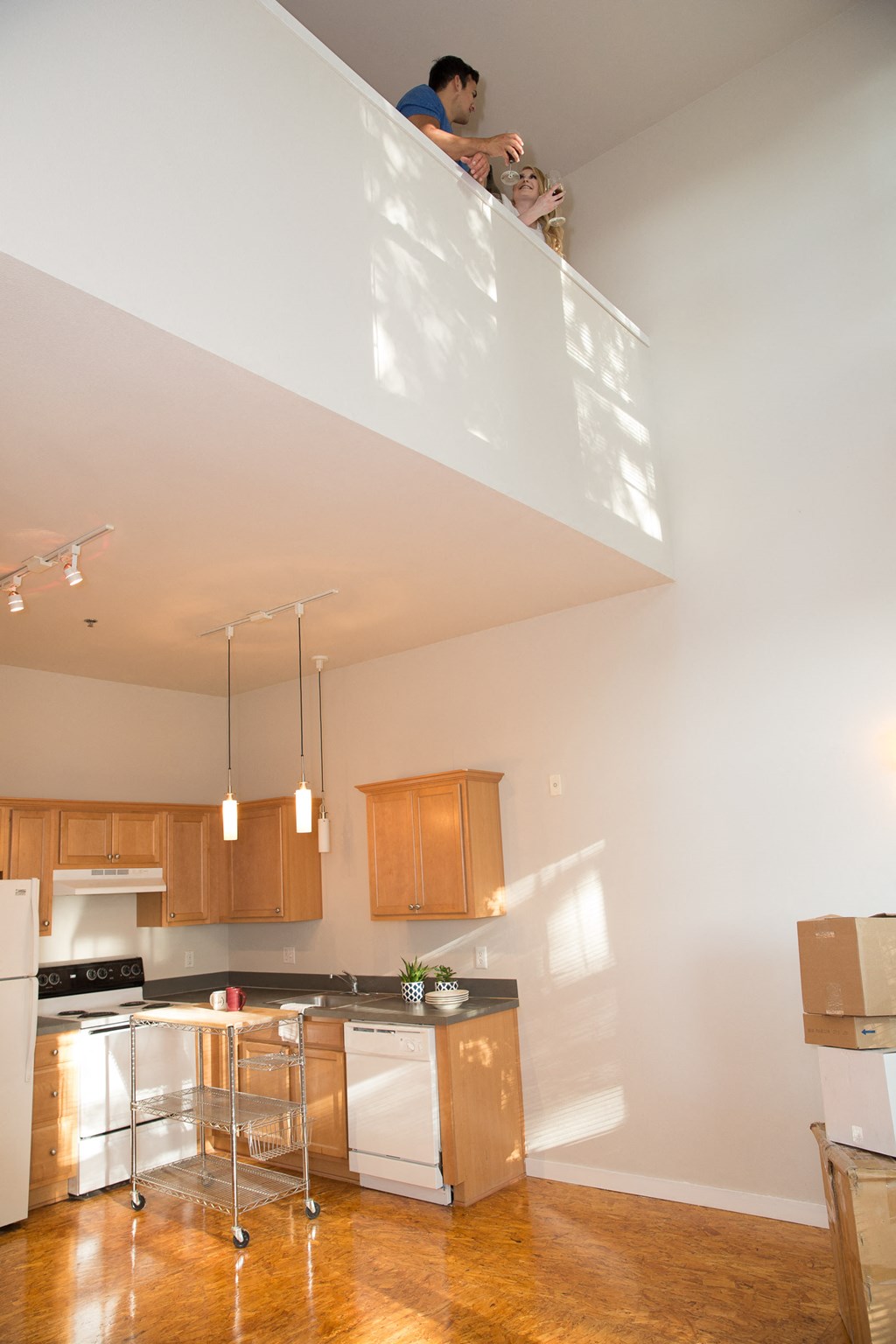 a view of a kitchen with a man on a balcony above it