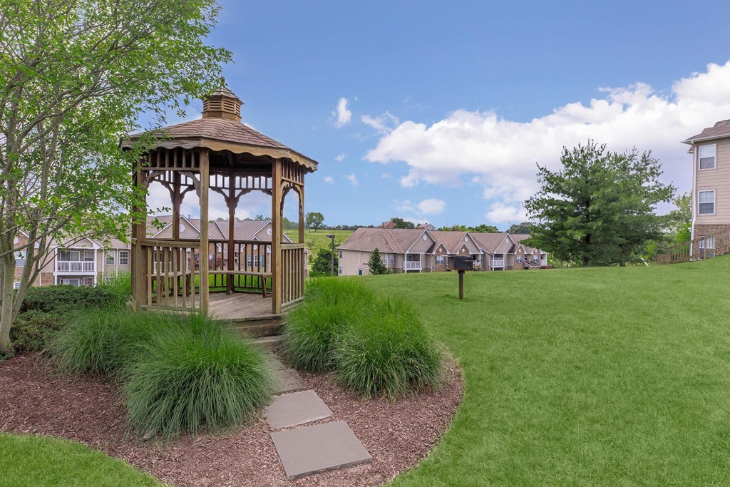 a gazebo in the middle of a yard with houses in the background
