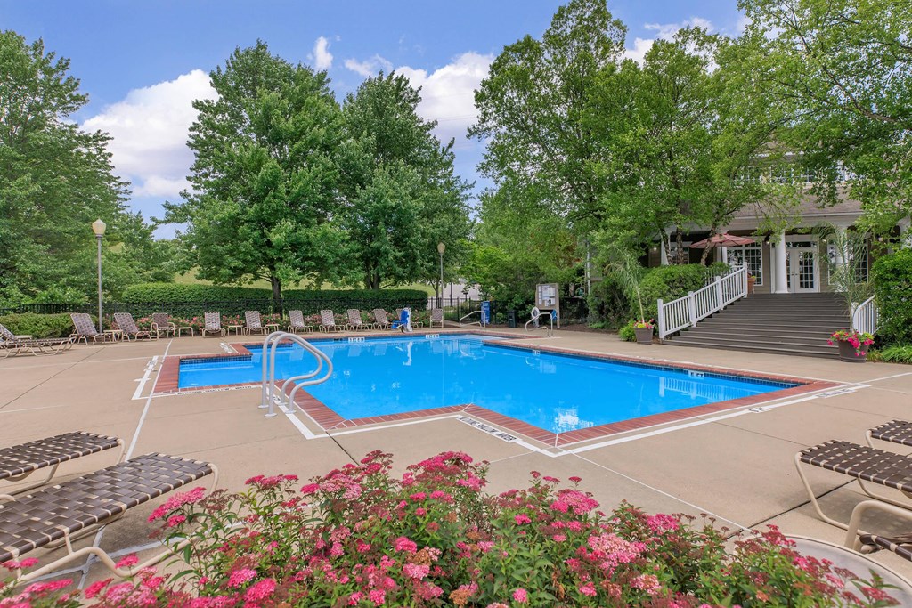 a swimming pool with chairs around it in front of a house