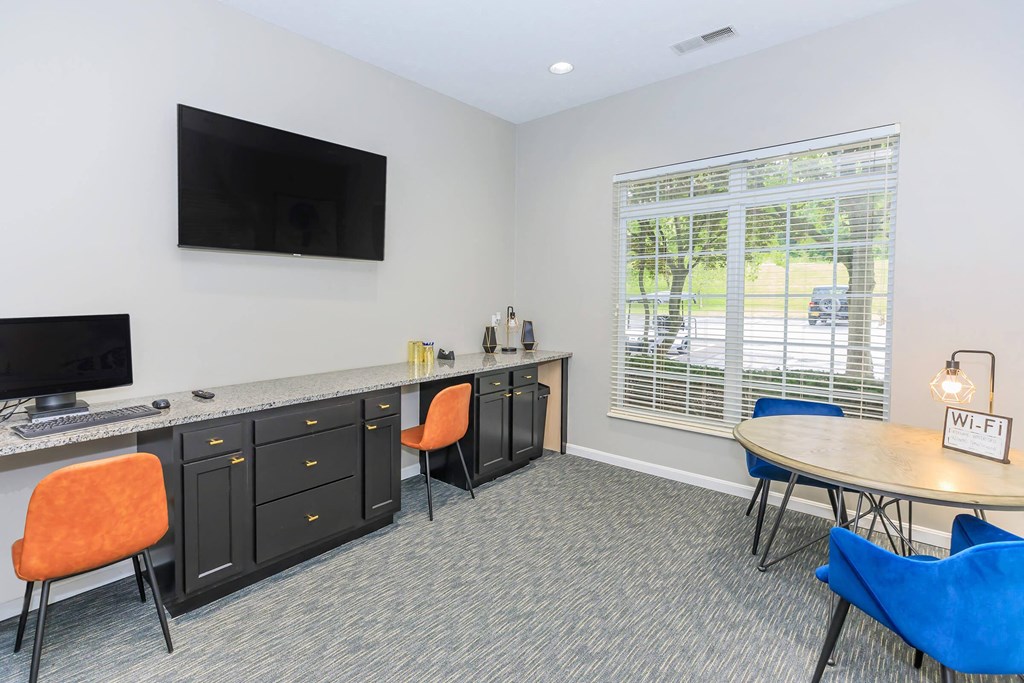a room with a desk and a television and a table and chairs