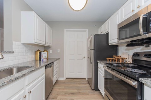 A kitchen with white cabinets and black appliances.
