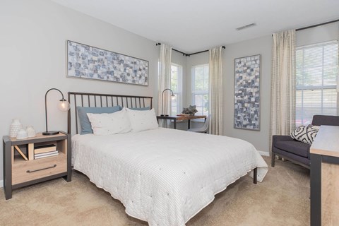 A bedroom with a large bed and a nightstand with a lamp.