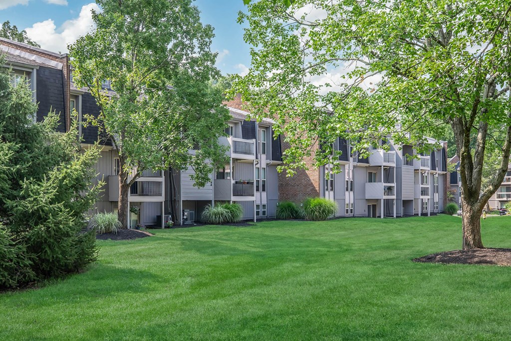 an exterior view of an apartment building with green grass and trees